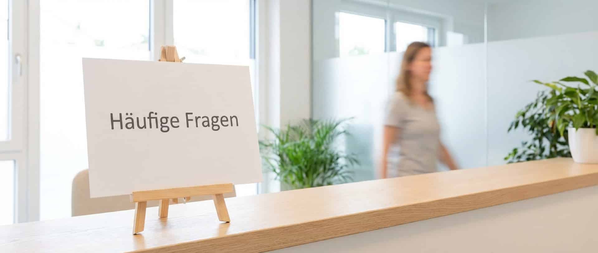 Schild mit der Aufschrift Häufige Fragen auf dem Tresen einer Heilpraxis